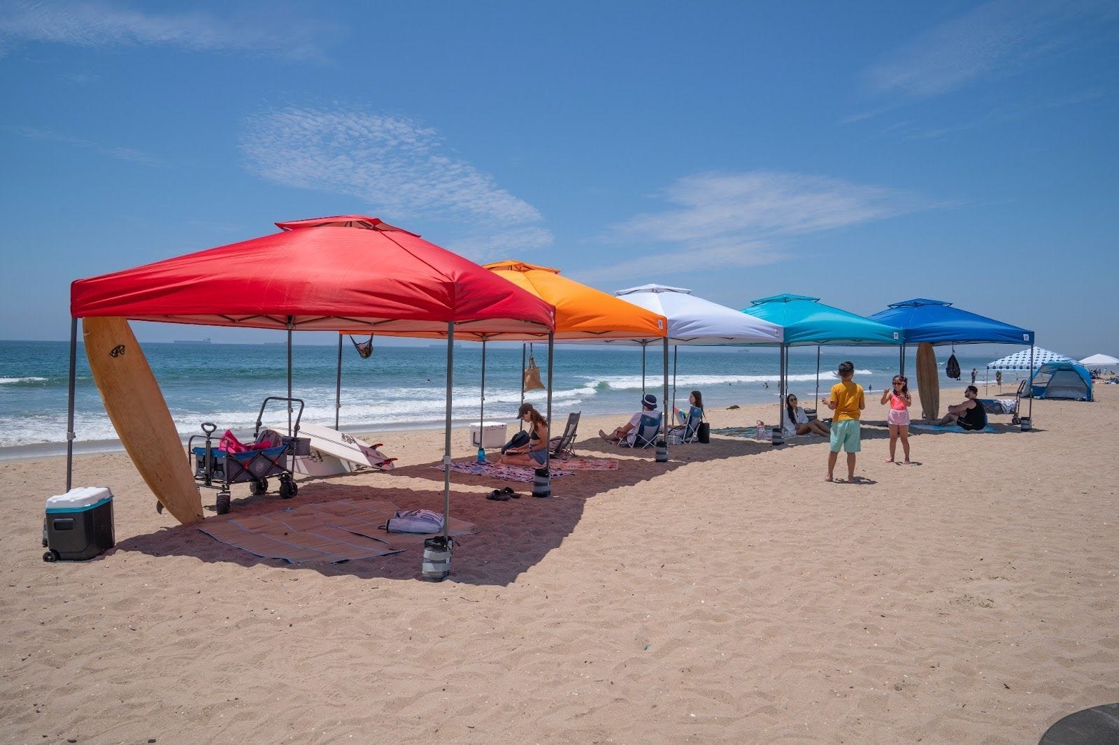 Colourful E-Z UP canopy tents set up along a beach